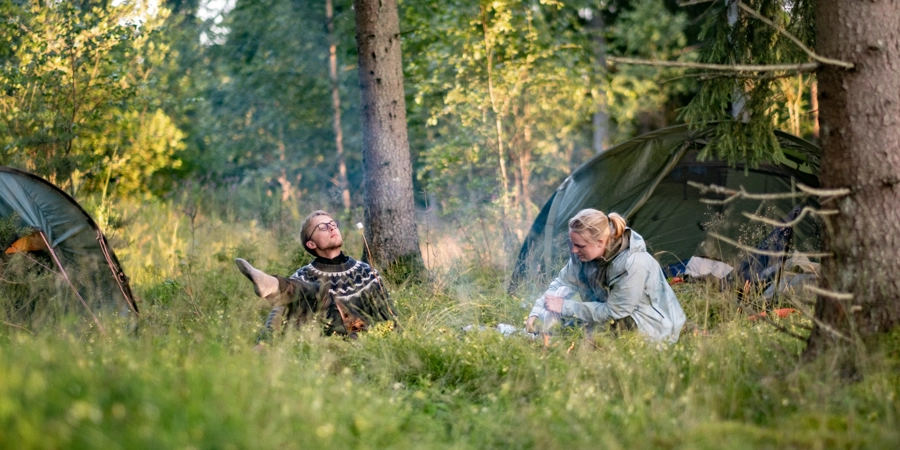 Människor som slagit läger och äter i det fria